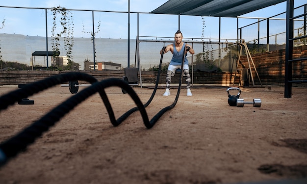 Foto homem forte fazendo exercícios com cordas