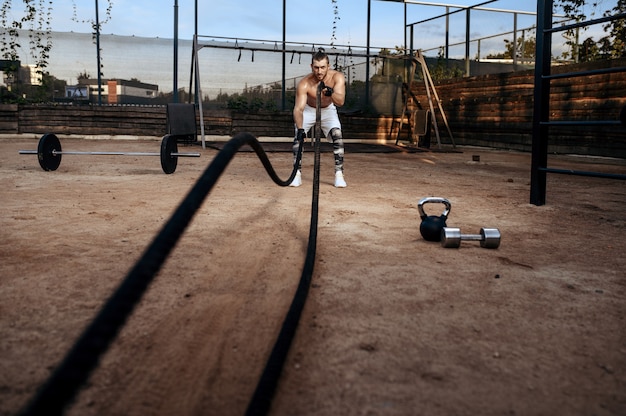 Homem forte fazendo exercícios com cordas