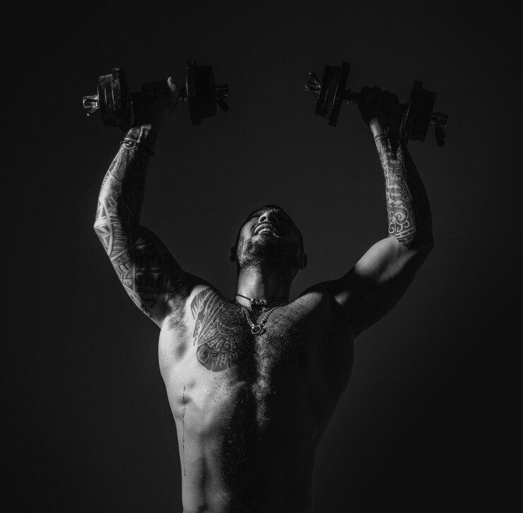 Foto homem forte levantando os halteres treino intenso corpo com tatuagem