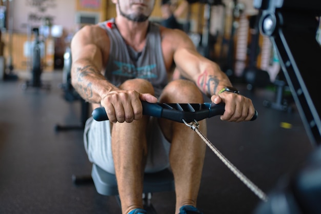 Homem forte remando usando uma máquina em uma academia