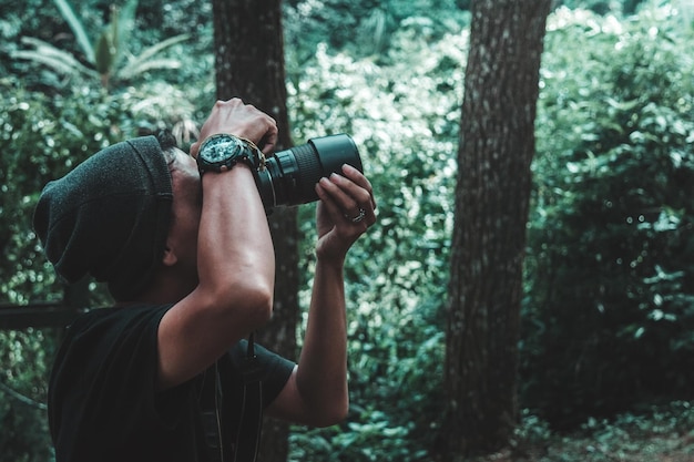 Foto homem fotografando através de câmera na floresta