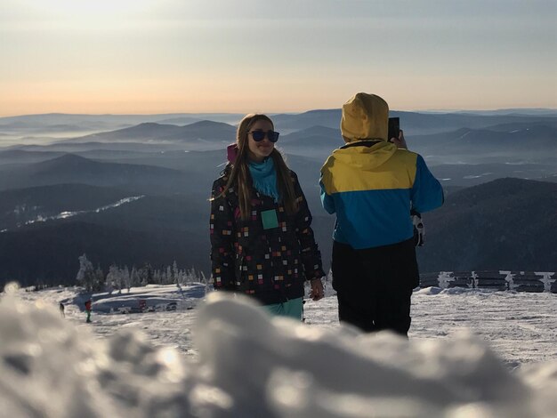 Foto homem fotografando montanhas com um amigo durante o inverno