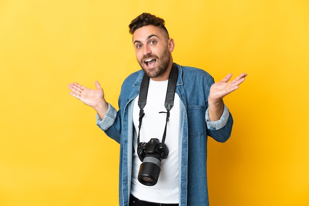 Homem fotógrafo isolado em um fundo amarelo com expressão facial chocada