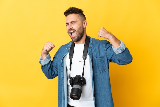 Homem fotógrafo isolado na parede amarela comemorando vitória