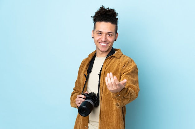 Homem fotógrafo sobre parede azul isolada convidando para vir