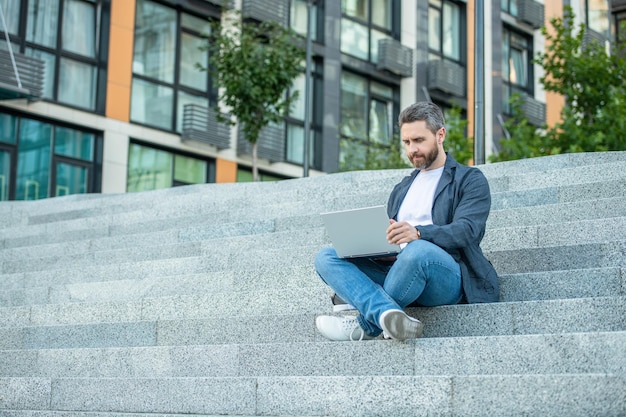 Homem freelancer com espaço de cópia ao ar livre para laptop homem freelancer na rua