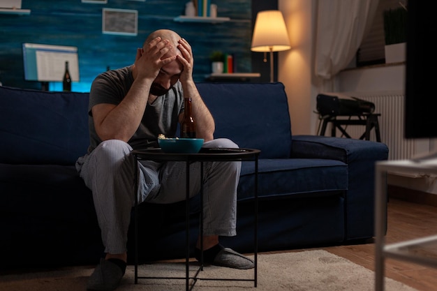 Homem frustrado assistindo esportes no programa de televisão e se sentindo triste com o time de futebol perdendo o jogo do campeonato. Fã de torcedor de futebol se sentindo chateado e emocionado com a derrota do jogo.