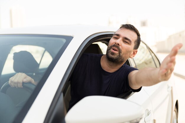 Foto homem frustrado fazendo gestos pela janela enquanto viaja de carro