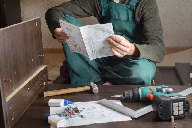 Homem frustrado lendo instruções e montando móveis de automontagem DIY nova casa e conceito de mudança