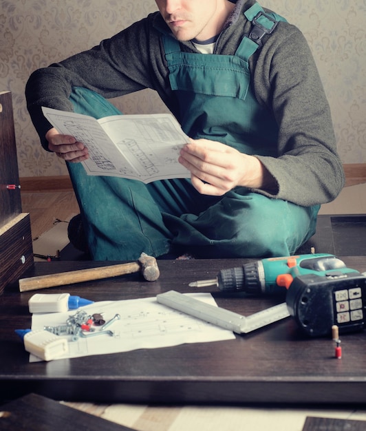 Homem frustrado lendo instruções e montando móveis de automontagem DIY nova casa e conceito de mudança