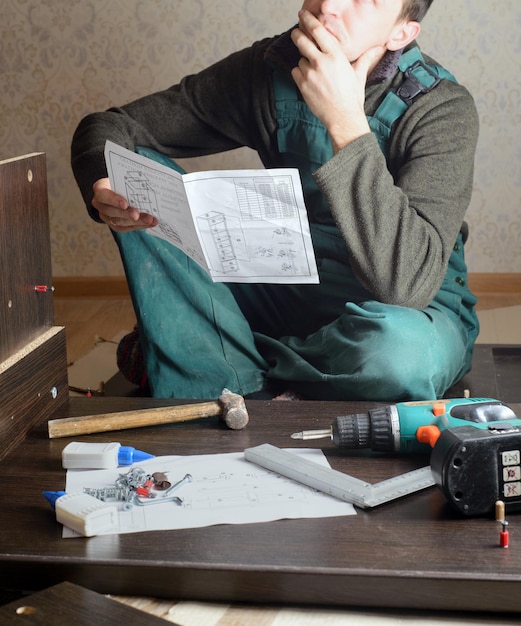 Homem frustrado lendo instruções e montando móveis de automontagem DIY nova casa e conceito de mudança