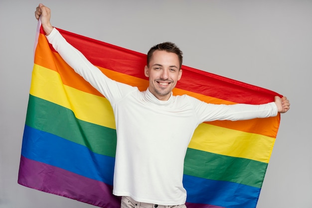 Homem gay sorridente com bandeira de arco-íris