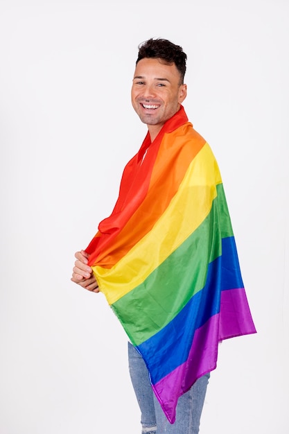 Foto homem gay sorrindo com bandeira do orgulho sobre os ombros