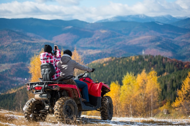 Homem gere quadbike, namorada sentada atrás dele faz foto