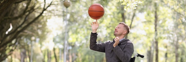 Homem gira basquete enquanto está sentado em cadeira de rodas na reabilitação do parque após lesão na coluna e