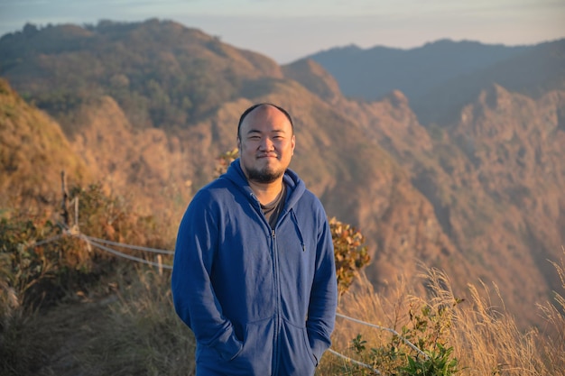 Homem gordo asiático com belo nascer do sol da montanha khao San nok wua kanchanaburiKhao San Nok Wua é a montanha mais alta do Parque Nacional Khao Laem É 1767 metros acima do nível do mar