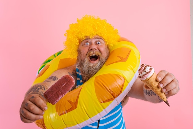 Homem gordo com barba e peruca comendo um picolé e um sorvete