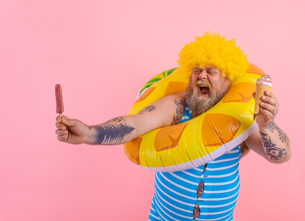 Homem gordo com barba e peruca comendo um picolé e um sorvete