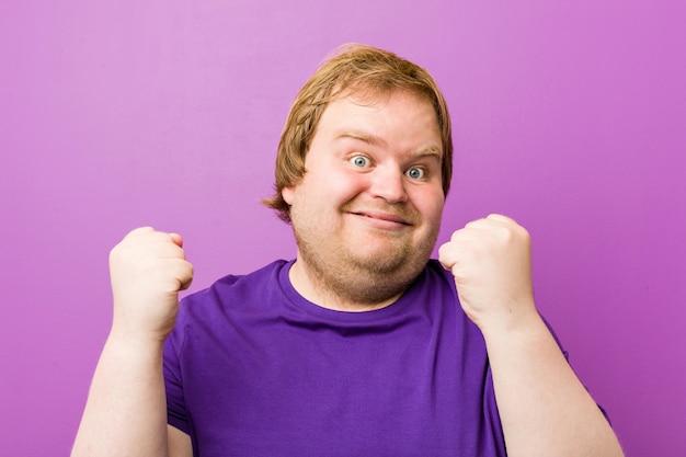 Homem gordo do ruivo autêntico novo que cheering despreocupado e entusiasmado. conceito de vitória.