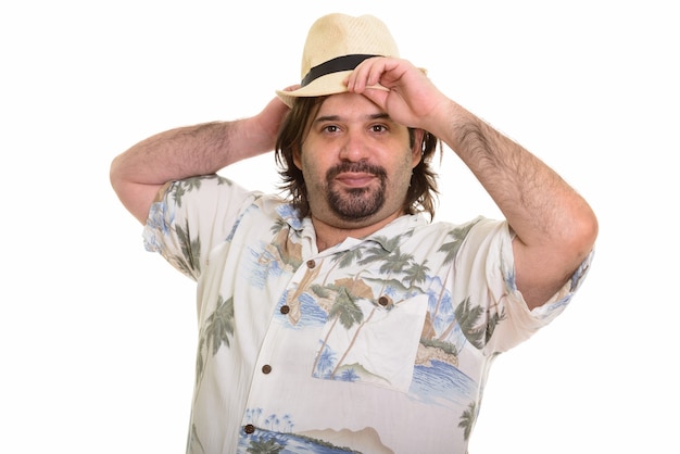 Homem gordo e caucasiano consertando chapéu, pronto para as férias, isolado no branco