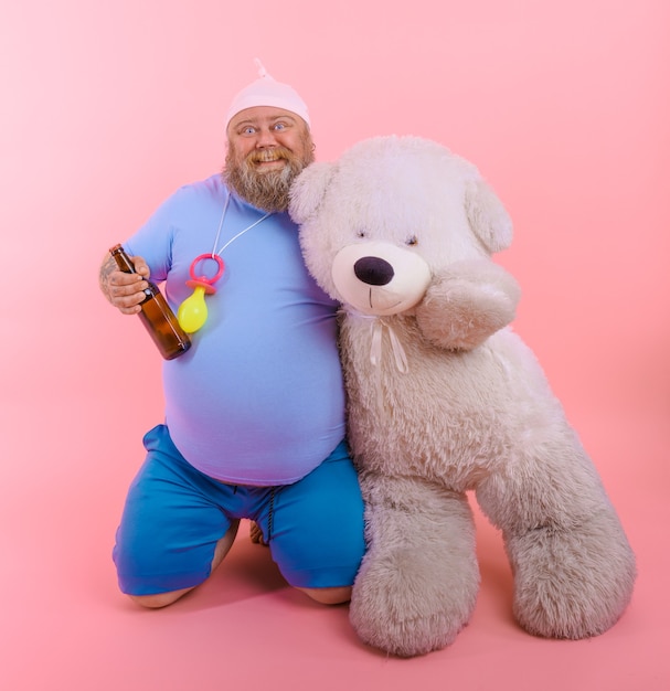 Foto homem gordo e feliz age como um bebê feliz, mas bebe cerveja