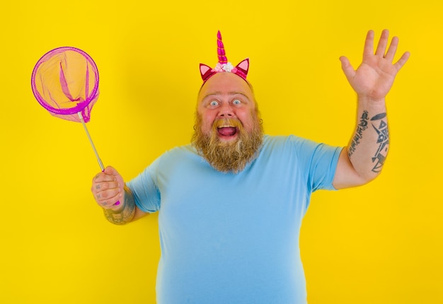 Homem gordo e feliz com bandana brincando com rede marítima