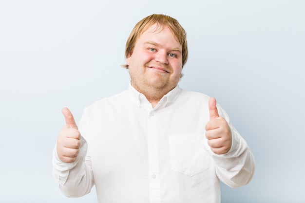 Homem gordo jovem ruiva autêntica com polegares para cima, um brinde por algo, apoiar e respeitar o conceito.