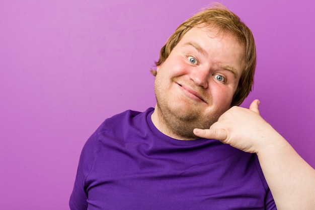 Homem gordo jovem ruiva autêntica, mostrando um gesto de chamada de telefone móvel com os dedos.
