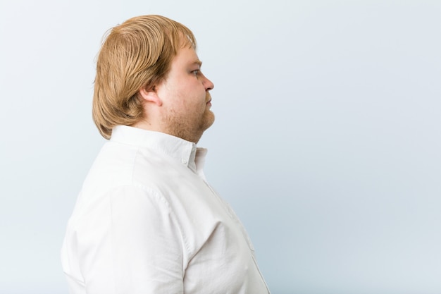 Homem gordo jovem ruiva autêntica, olhando para a esquerda, pose de lado.