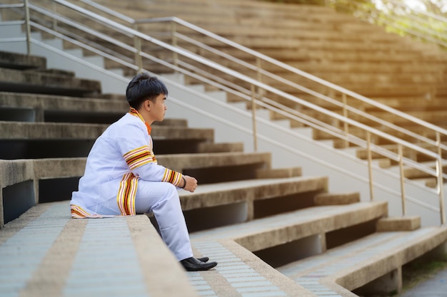 Homem graduados universitários em vestido de formatura sentado na escada