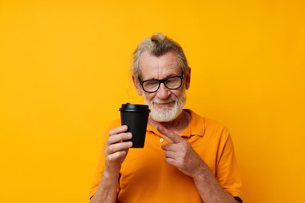 Homem grisalho sênior com fundo amarelo de copo descartável preto