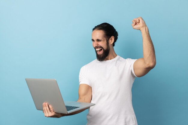 Homem gritando de alegria e segurando o laptop regozijando-se com a vitória nas apostas online