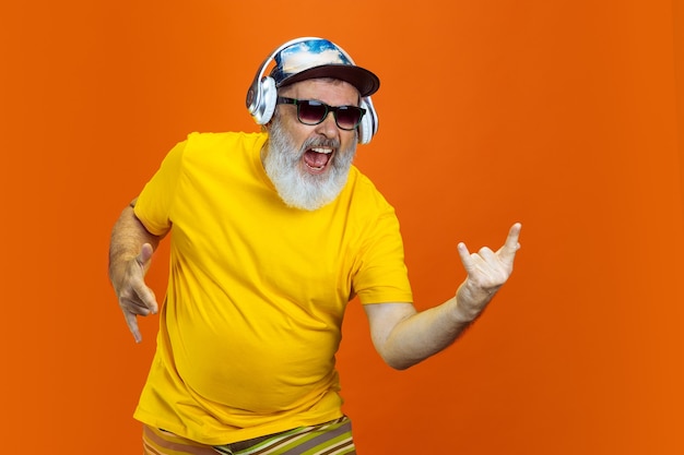 Homem hippie sênior usando dispositivos, gadgets em fundo laranja