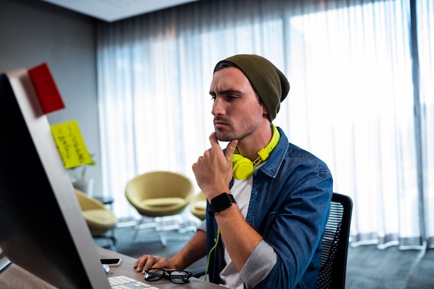 Homem hipster concentrado trabalhando com fone de ouvido de áudio