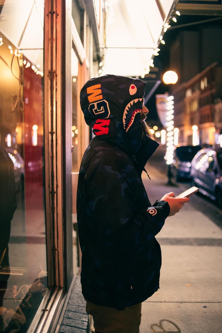 Foto homem hipster irreconhecível com capuz moderno com smartphone na passarela foto
