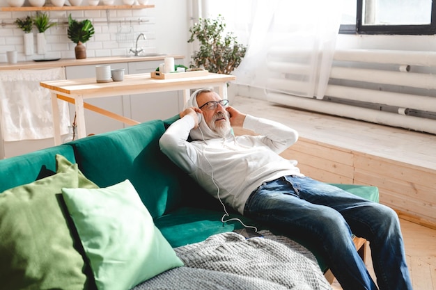 Foto homem hipster sênior usando telefone enquanto ouve música de lista de reprodução no aplicativo móvel homem idoso usando máscara protetora facial enquanto assiste a vídeo no smartphone