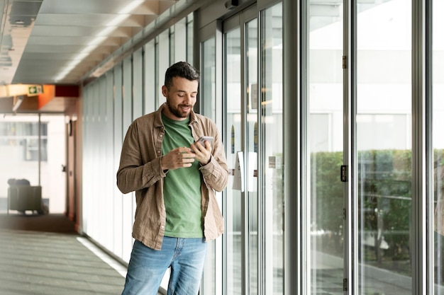 Homem hipster sorridente usando telefone celular para fazer compras on-line dentro de casa Influenciador de sucesso feliz