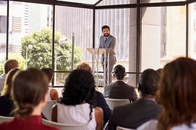 Homem hispânico apresentando seminário de negócios, apoiando-se no púlpito