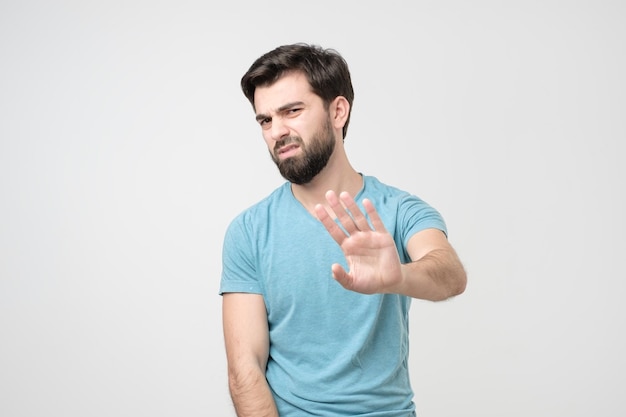 Homem hispânico bonito fazendo sinal de stop, recusando-se a receber o prêmio