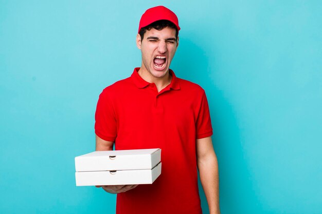 Homem hispânico bonito gritando agressivamente olhando conceito de entrega de pizza com muita raiva