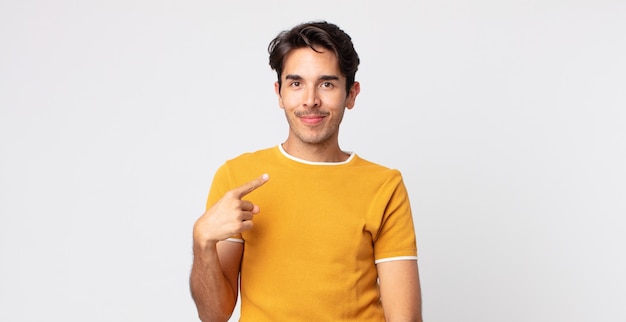 Homem hispânico bonito, orgulhoso, confiante e feliz, sorrindo e apontando para si mesmo ou fazendo o primeiro sinal