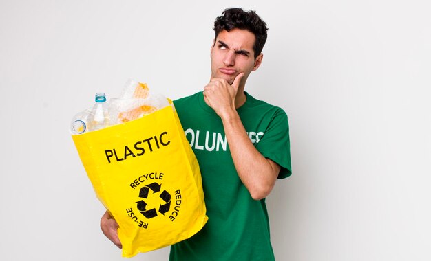 Homem hispânico bonito pensando sentindo o conceito de ecologia duvidoso e confuso