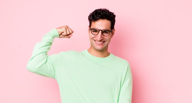 Homem hispânico bonito se sentindo feliz satisfeito e poderoso ajuste de flexão e bíceps musculosos parecendo forte depois da academia