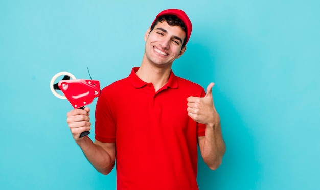 Homem hispânico bonito se sentindo orgulhoso sorrindo positivamente com polegares para cima conceito de empacotador