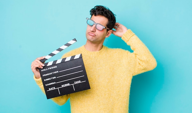 Homem hispânico bonito sorrindo alegremente e sonhando acordado ou duvidando do conceito de cinema