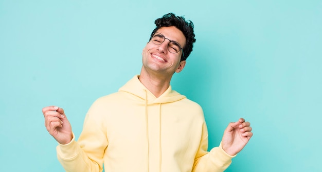 Homem hispânico bonito sorrindo sentindo-se despreocupado relaxado e feliz dançando e ouvindo música se divertindo em uma festa