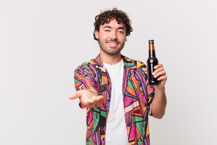 Foto homem hispânico com cerveja sorrindo feliz com olhar amigável, confiante e positivo, oferecendo e mostrando um objeto ou conceito