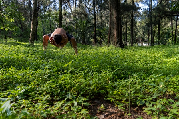 Homem hispânico e latino meditando no meio de uma floresta recebendo raios solares pele marrom méxico