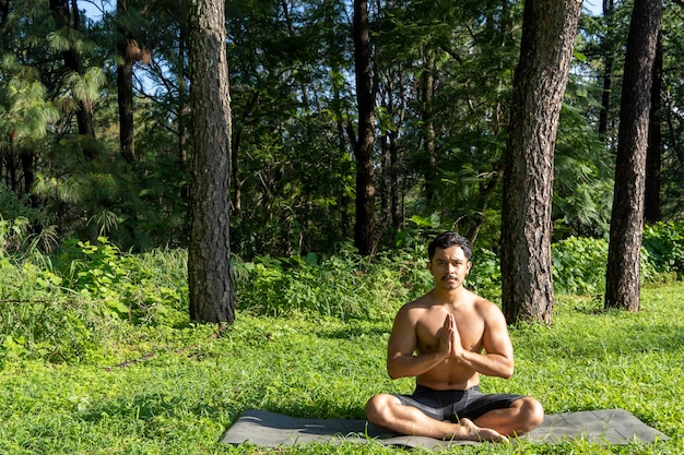 Homem hispânico e latino meditando no meio de uma floresta recebendo raios solares pele marrom méxico