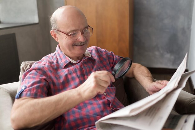 Homem hispânico sênior lendo jornal com lupa